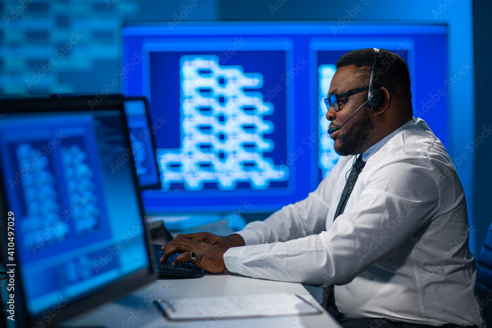 Call-center worker is speaking with the client by headset. Workplace of the african-american support operator. Call-center worker is speaking with the client by headset. Workplace of the african-american support operator.