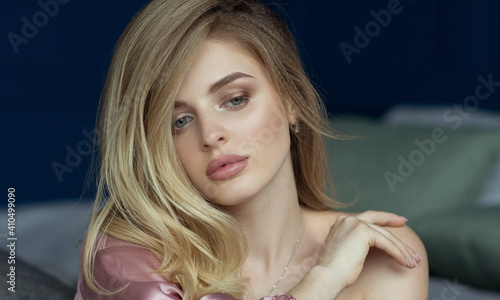Canvas Print Close-up portrait of young beautiful blonde woman with wavy hair in a pink peignoir with a plunging neckline