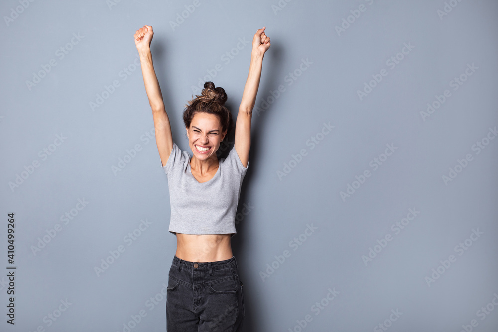 Winner joyful woman with hands up celebrating success isolated against background of a gray wall. Winner joyful woman with hands up celebrating success isolated against background of a gray wall.