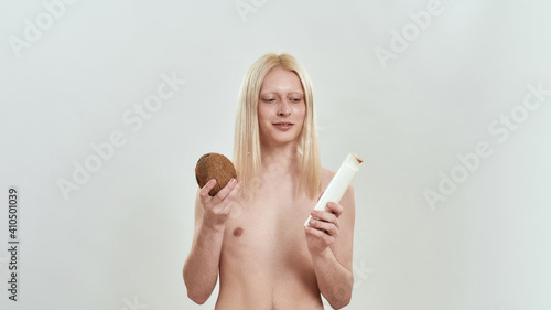Happy young caucasian boy holding shampoo bottle and coconut