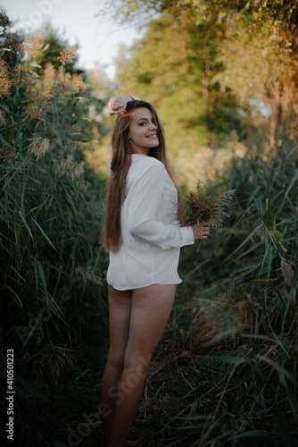 Sexy girl in a white shirt on nature in the evening in the sunset rays of the sun