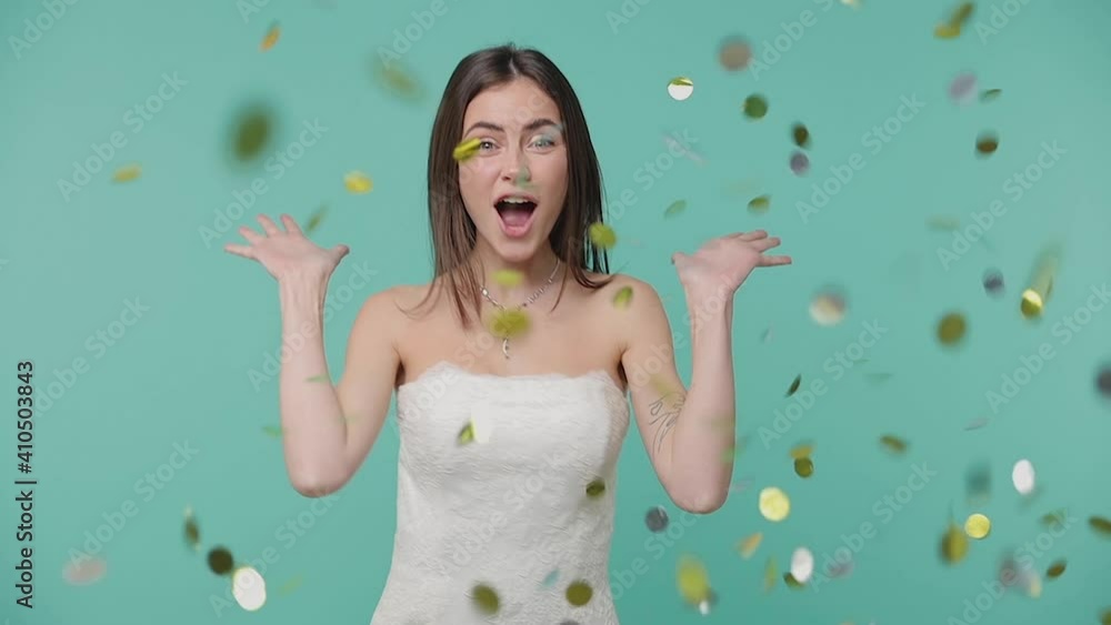 Surprised cheerful bride young woman 20s in white wedding dress isolated on blue turquoise background studio. Wedding concept. Say wow spreading hands doing winner gesture celebrating with confetti Surprised cheerful bride young woman 20s in white wedding dress isolated on blue turquoise background studio. Wedding concept. Say wow spreading hands doing winner gesture celebrating with confetti