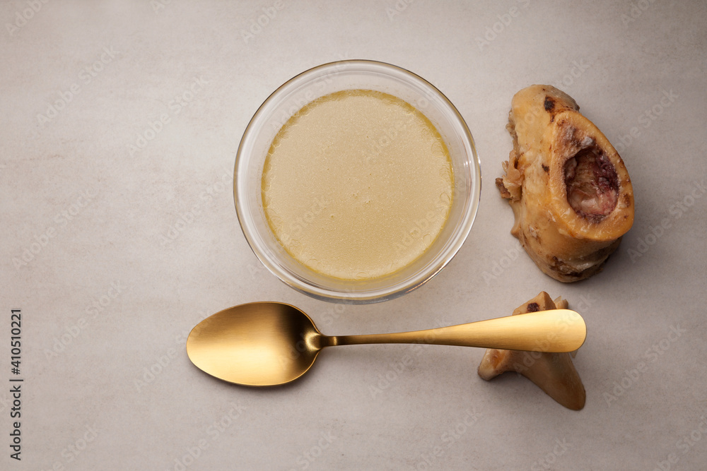 Bone broth in glass bowl. Top view, copy space. Beef bones are source of natural collagen, which is useful for joints and provides body with essential amino acids Bone broth in glass bowl. Top view, copy space. Beef bones are source of natural collagen, which is useful for joints and provides body with essential amino acids