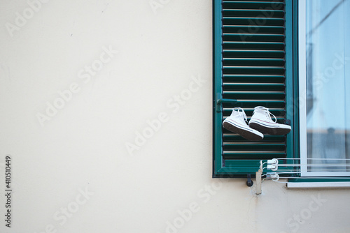 Drying white sneakers on a green window& Conception: unusual, strange, peculiar