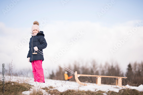 Little girl enjoying a sleigh ride. Child sledding. 