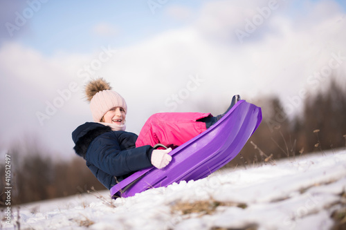 Little girl enjoying a sleigh ride. Child sledding. 