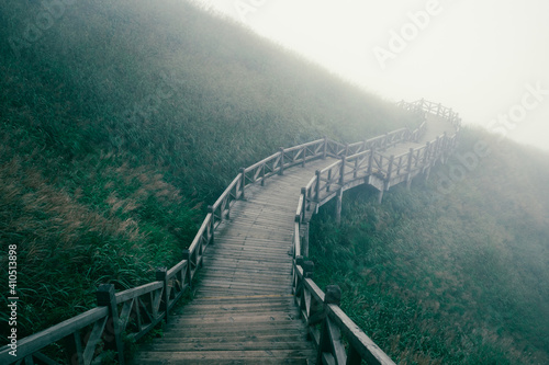 Wooden plank path between meadow covered in fog on top of Wugong Mountain in Jiangxi, China