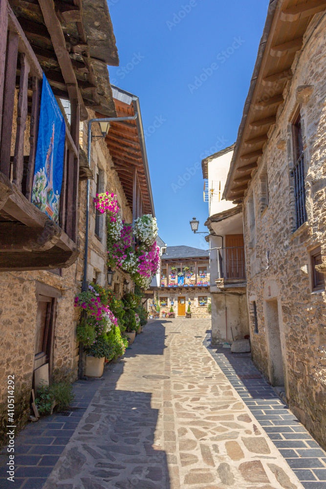 Obraz premium Puebla de Sanabria, Spain - September 6, 2020: Cobblestone street with picturesque stone residential buildings and flowered balconies in Puebla de Sanabría, Zamora province, Castilla y León.