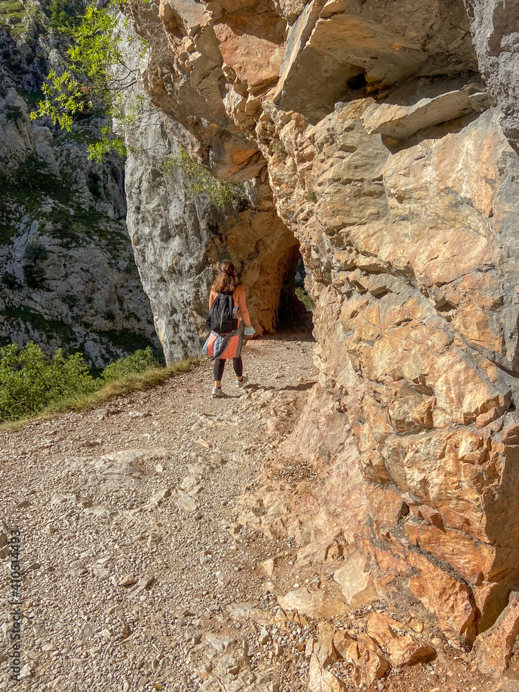 Cain, Spain - September 1, 2020: Female hiking trough the Cares Route in the heart of Picos de Europa National Park, Spain. Narrow and impressive canyon between cliffs, bridges and footpaths.