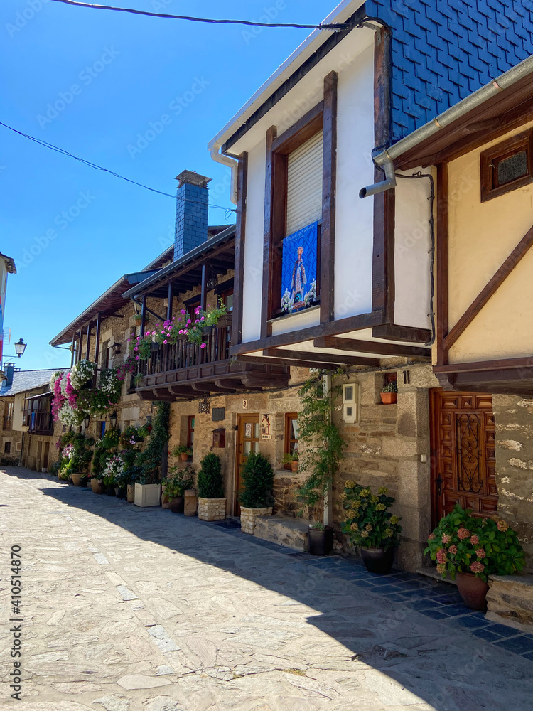 Puebla de Sanabria, Spain - September 6, 2020: Cobblestone street with picturesque stone residential buildings and flowered balconies in Puebla de Sanabría, Zamora province, Castilla y León. Puebla de Sanabria, Spain - September 6, 2020: Cobblestone street with picturesque stone residential buildings and flowered balconies in Puebla de Sanabría, Zamora province, Castilla y León.