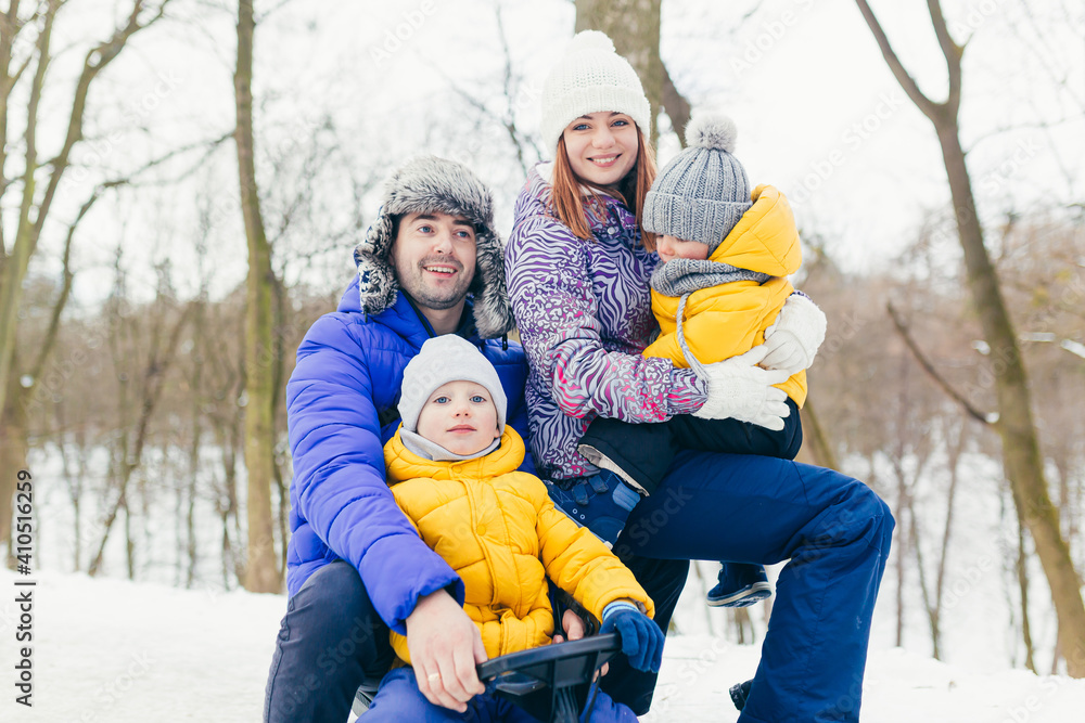 Obraz premium Happy family walking in winter park together, two adult man and woman and two children