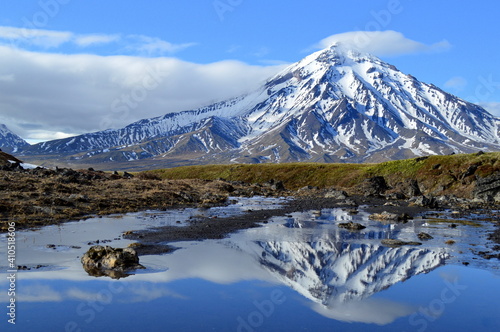 Tableau sur toile A snowy volcano mirrowing in a lake in the wilderness at Tolbachik volcano in Ka