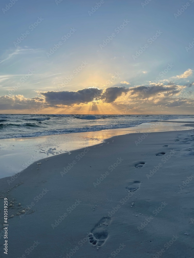 footprints in the sand with sunset skies on Florida Emerald Coast beach
