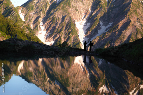 朝日を浴びて輝く北アルプスと八方池と登山者