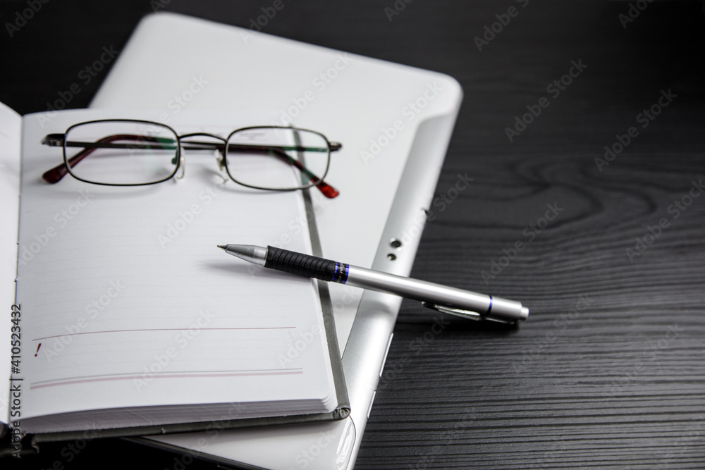 Workplace with tablet, glasses and pen on a black background Workplace with tablet, glasses and pen on a black background