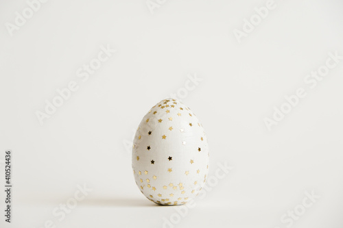 Easter white egg with glitter stars isolated on white background. Minimal easter concept. Happy Easter card with copy space for text. Top view, flatlay. Concept for banner, flyer, invitation, greeting