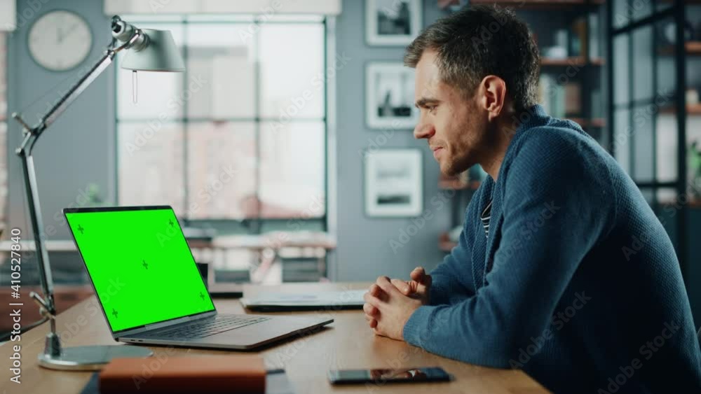 Handsome Caucasian Specialist Chatting on Video Call on Laptop with Green Screen Mock Up Display at Home Living Room. Freelance Man Chatting to Clients Over Internet on Social Networks. Handsome Caucasian Specialist Chatting on Video Call on Laptop with Green Screen Mock Up Display at Home Living Room. Freelance Man Chatting to Clients Over Internet on Social Networks.