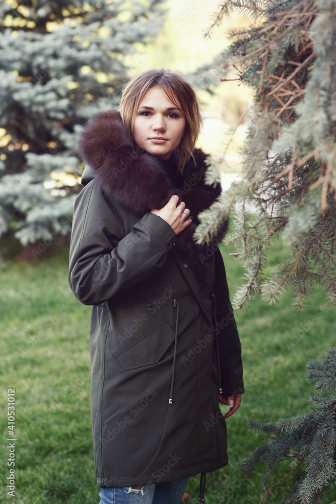  blond business woman in fox fur down jacket with hood close up photo on city park background