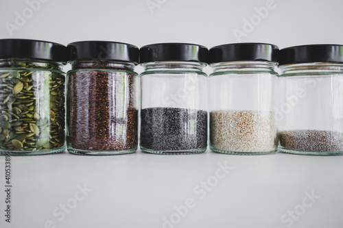 seed jars with sesame poppy pupmkin chia and flax seeds as important nutrient sources for nutrition shot on white background photo