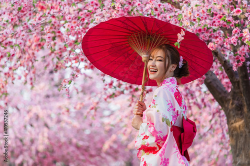 Wallpaper Mural woman in yukata (kimono dress) holding umbrella and looking sakura flower or che