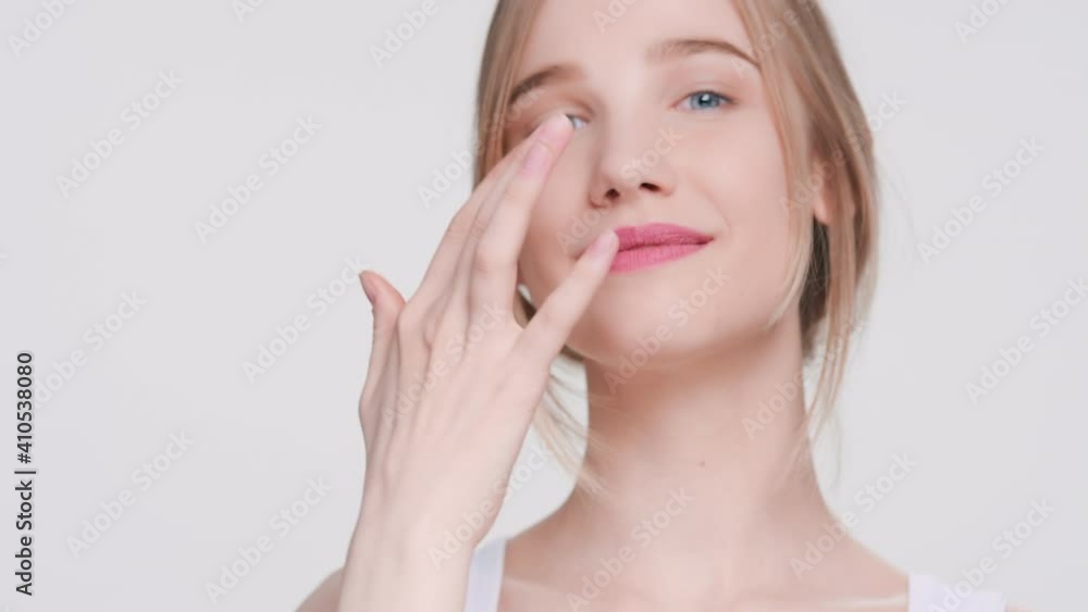 Young gorgeous beauty model demonstrates easiness of applying moisturizing cream on her face | Skin care products advertising concept Young gorgeous beauty model demonstrates easiness of applying moisturizing cream on her face | Skin care products advertising concept