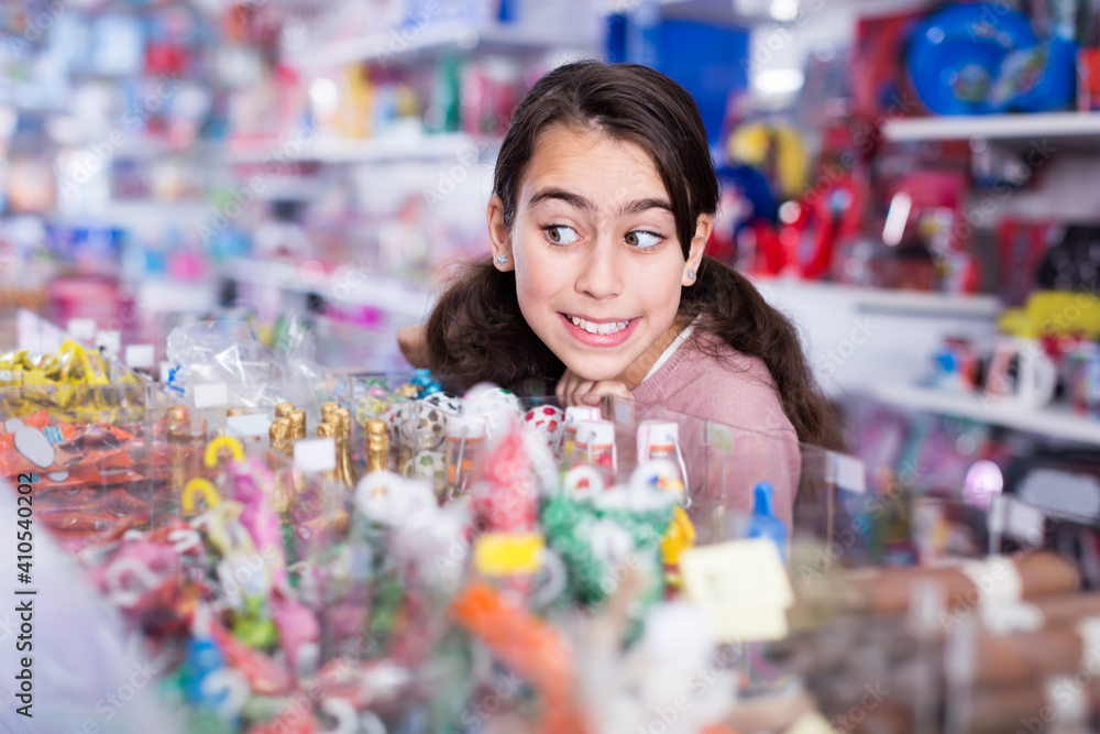 vigorous schoolgirl delighted with choosing lollipop in candy store