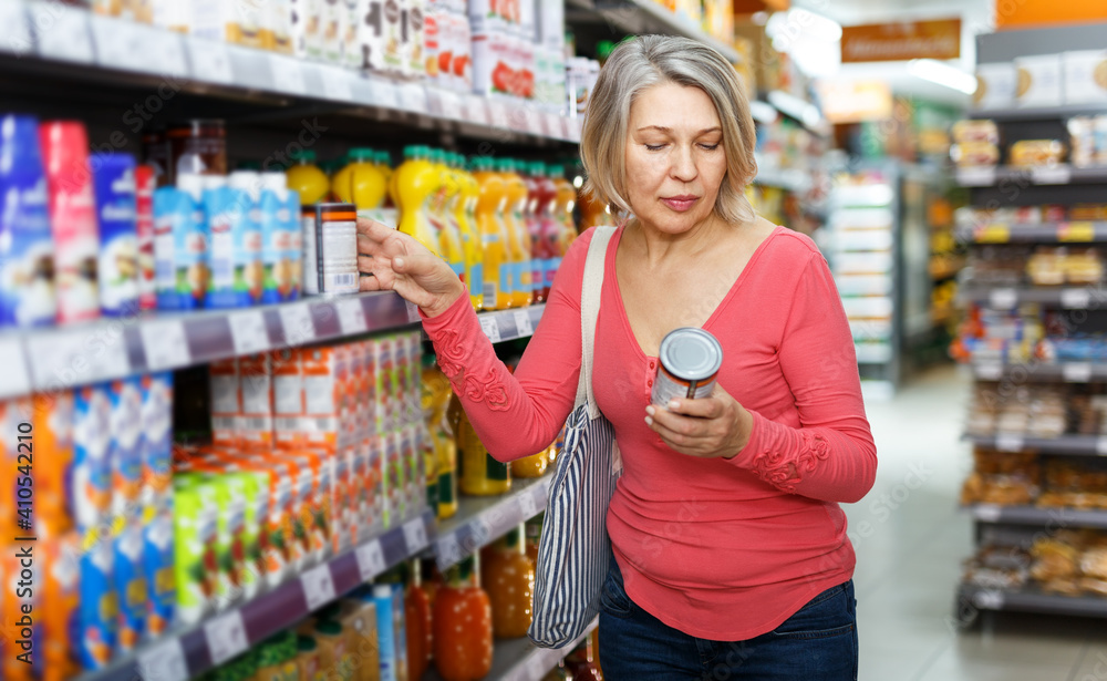 Portrait of casual mature woman doing shopping in food department of supermarket