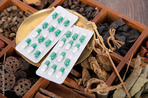 Western medicine capsule on the traditional Chinese medicine storage box photo