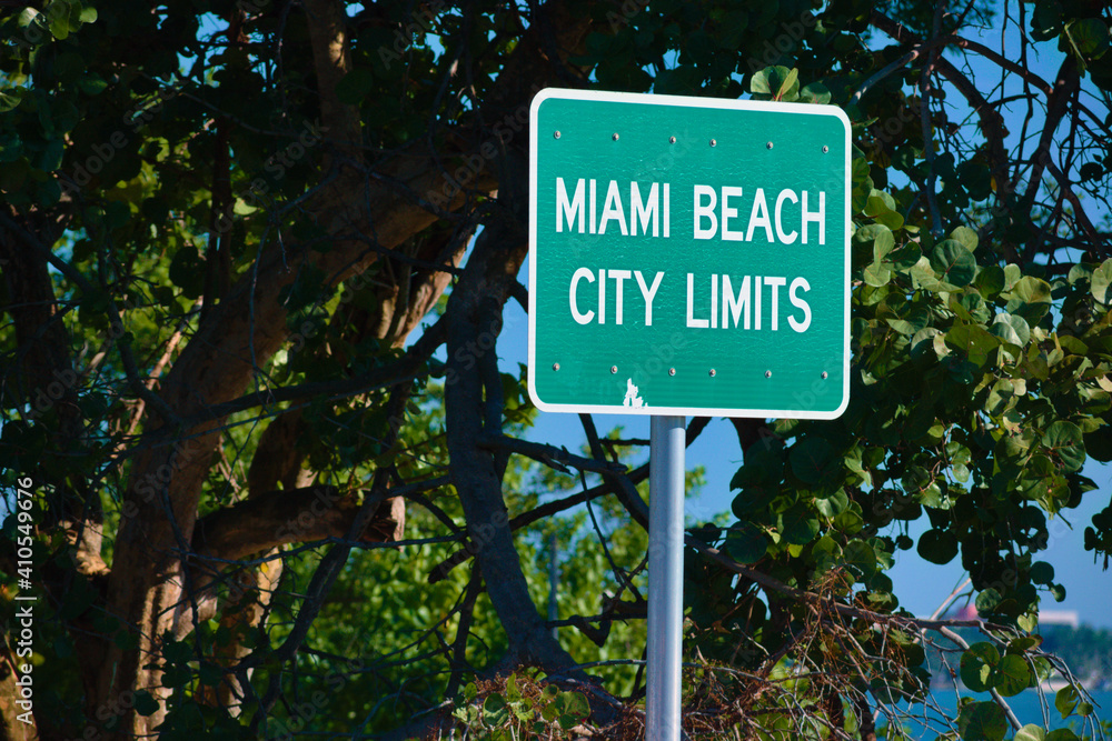 Green Miami Beach city limits traffic entrance text sign driving on interstate highway road near tropical tree park beach border