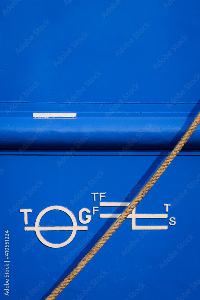 White Plimsoll mark on blue rustproof steel hull surface of large vessel with mooring rope in vertical frame White Plimsoll mark on blue rustproof steel hull surface of large vessel with mooring rope in vertical frame