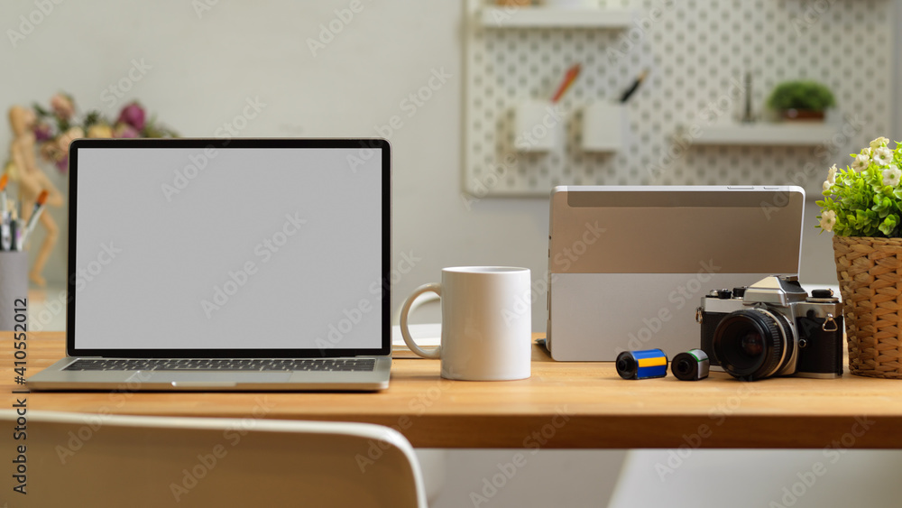 Fototapeta premium Cropped shot of office room with laptop, mug and camera on the table