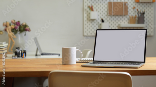 Close up view of office room with laptop, mug and copy space on the table