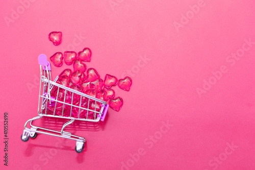 Valentine's day, endless love or special occasion concept : Top view of red hearts spilled out of a shopping cart. isolated on pink background. copy space.