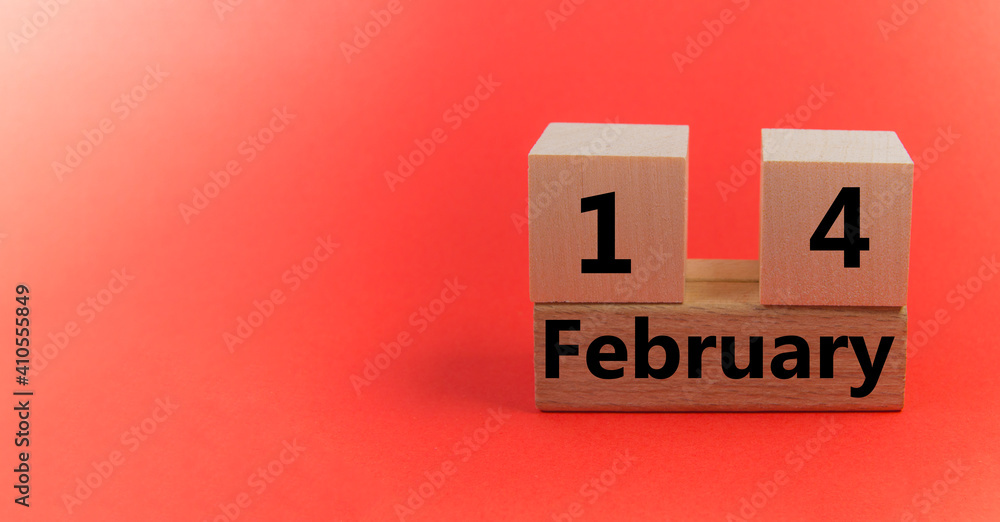 Wooden block calendar with the date February 14 on a red festive background with a copy of the space Wooden block calendar with the date February 14 on a red festive background with a copy of the space