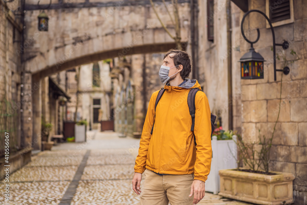 Young man wearing a medical mask during COVID-19 coronavirus tourist walks down the street in a European city after the end of COVID-19 coronavirus. quarantine