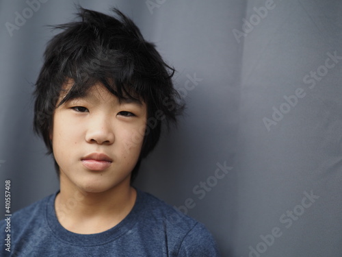 Funny portrait of 11 years old asian boy with dark blue t shirt 