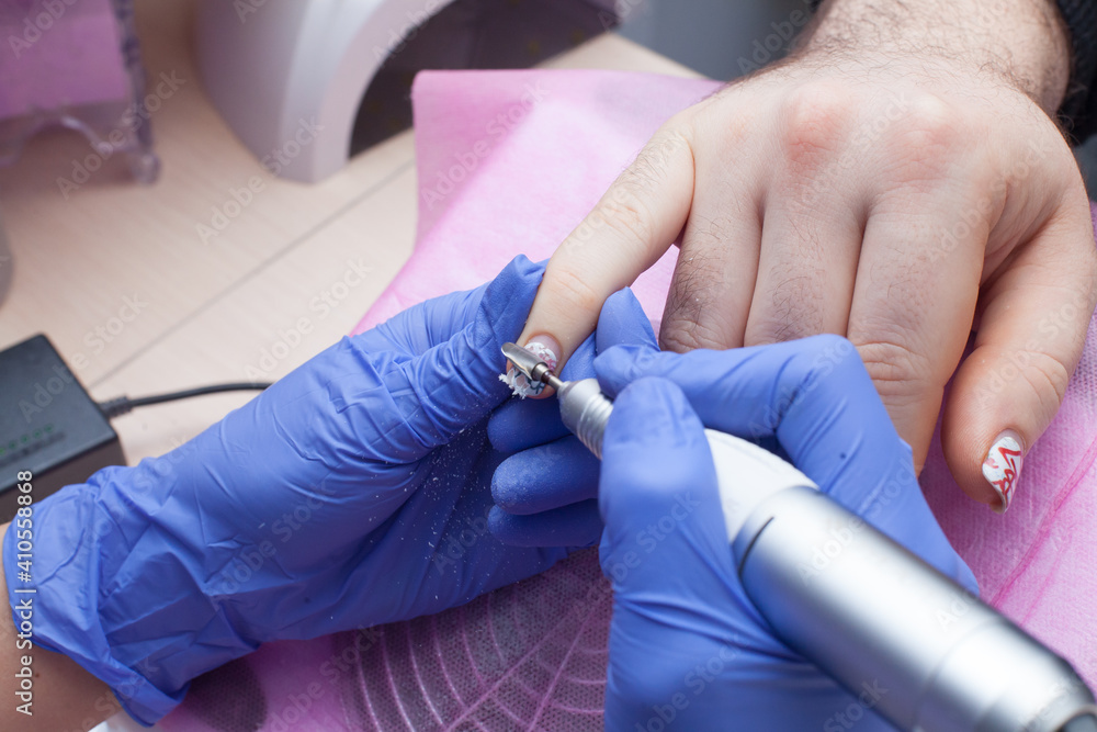 Male manicure in the salon. The process of removing the gel polish, cleaning the nail plate, forming the shape.. Male manicure in the salon. The process of removing the gel polish, cleaning the nail plate, forming the shape..