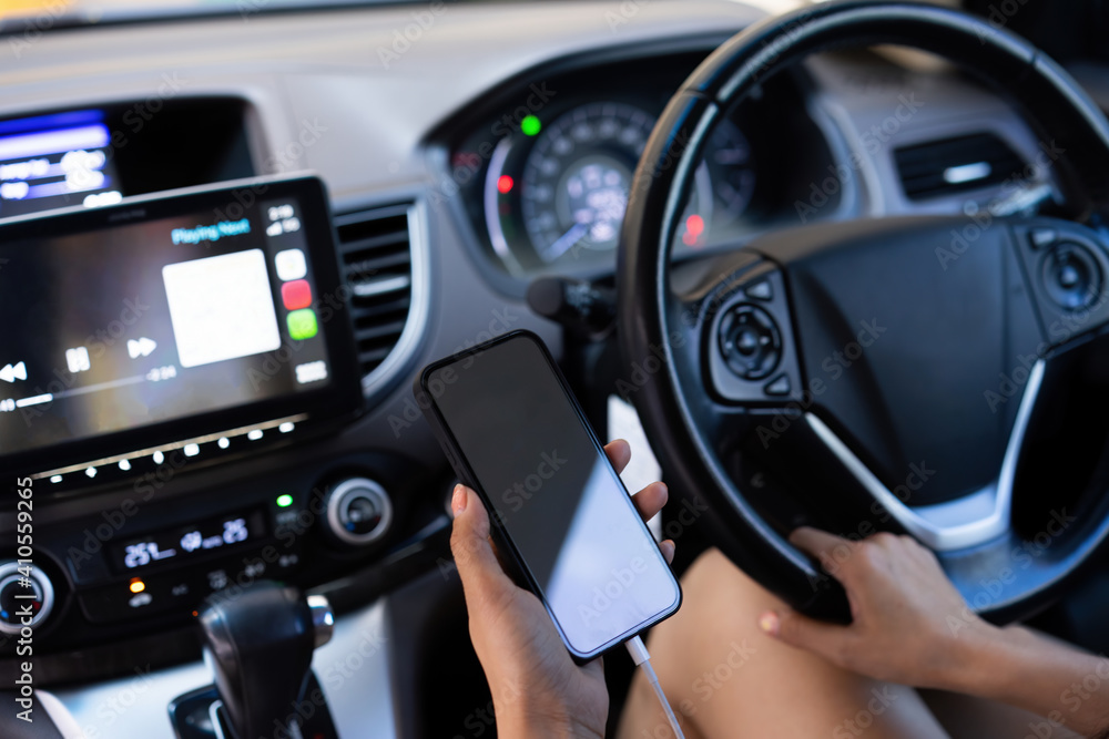 Cropped shot of woman hand using mockup smartphone while driving a car.