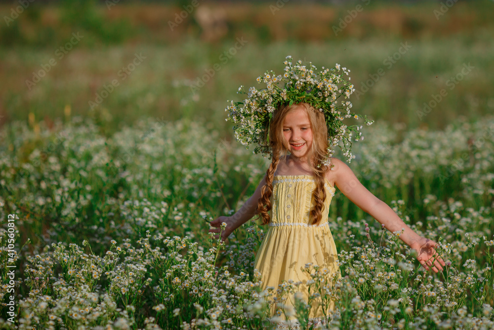 Fototapeta premium little girl in the field with a wreath on her head walking summer