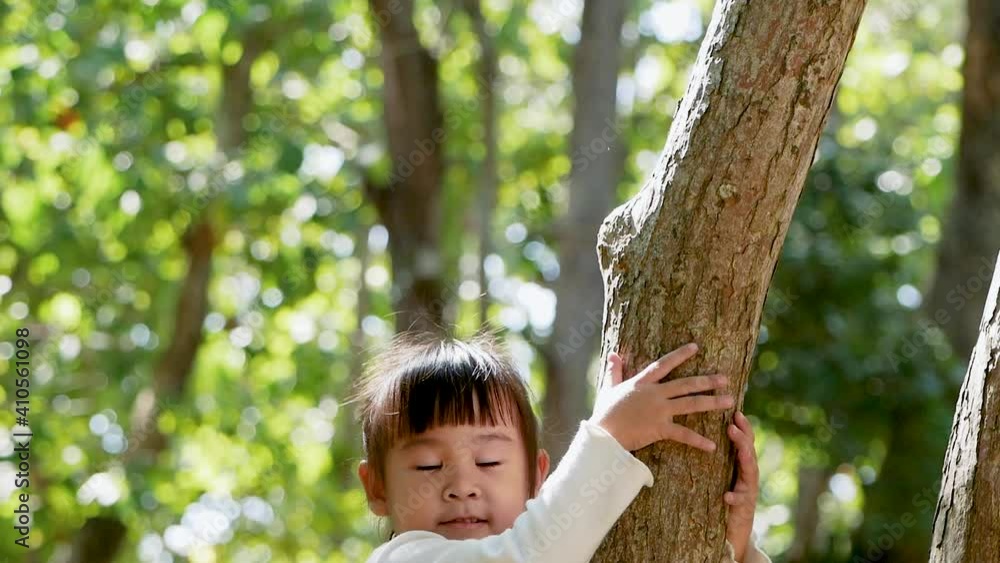 adorable little girl in long sleeve T-shirt climbs a tree outdoor in a summer park. Happy childhood. adorable little girl in long sleeve T-shirt climbs a tree outdoor in a summer park. Happy childhood.
