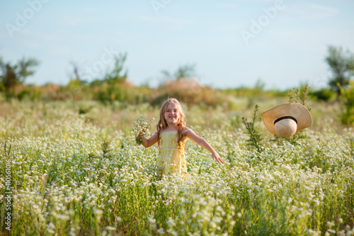 little girl in a straw hat in the field throws, indulges