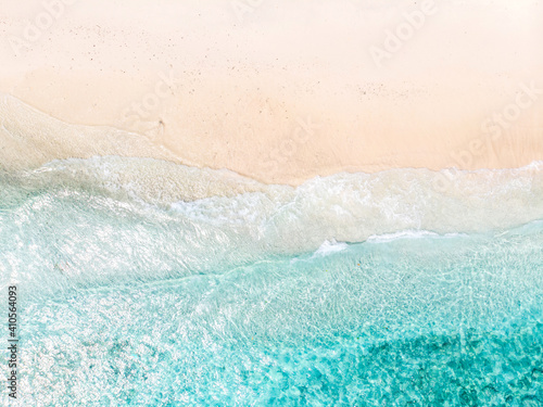 Aerial view of clear sea waves and white sandy beach in summer.