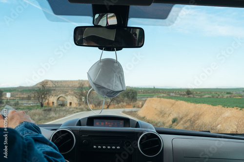 Medical mask hanging inside car, life after coronavirus pandemic.Concept of virus protection while driving or traveling