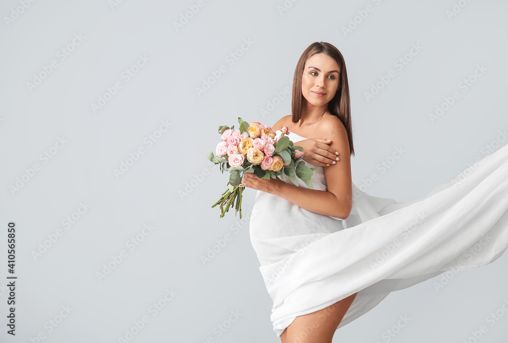 Beautiful pregnant woman with flowers on light background Beautiful pregnant woman with flowers on light background