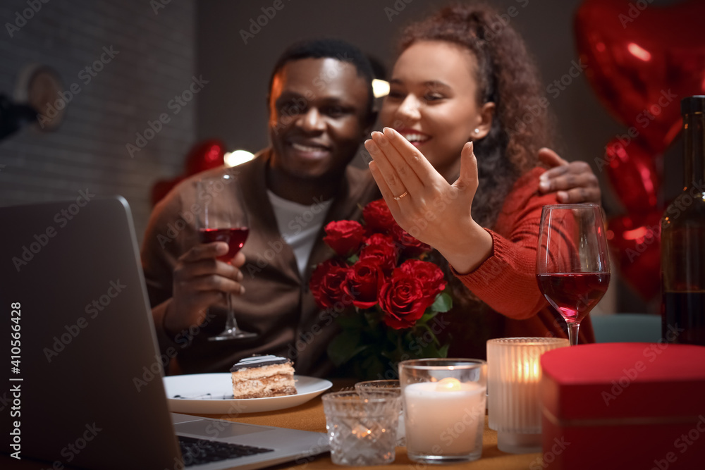Happy engaged African-American couple video chatting with friends on Valentine's Day at home