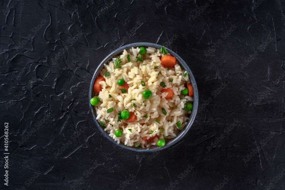 Rice with vegetables, shot from above on a dark black background