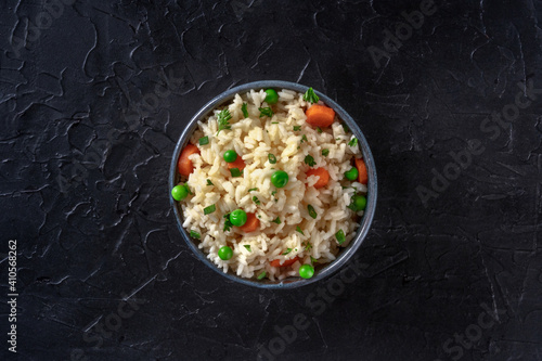 Rice with vegetables, shot from above on a dark black background