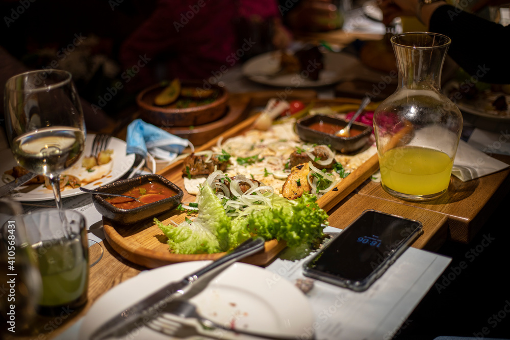 festive table with wine and mixed meat with salad and sauce on a chalkboard with lemonade for company, horizontal