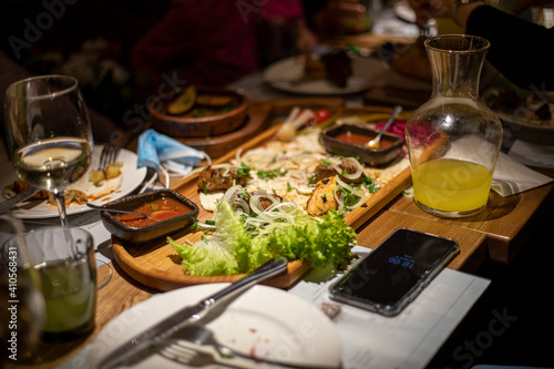 festive table with wine and mixed meat with salad and sauce on a chalkboard with lemonade for company  horizontal