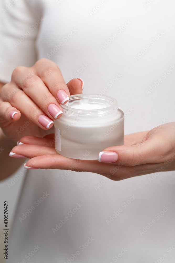 Close-up of a young girl holding an open jar of cosmetic cream in her hands. Skin care and beauty concept. Close-up of a young girl holding an open jar of cosmetic cream in her hands. Skin care and beauty concept.